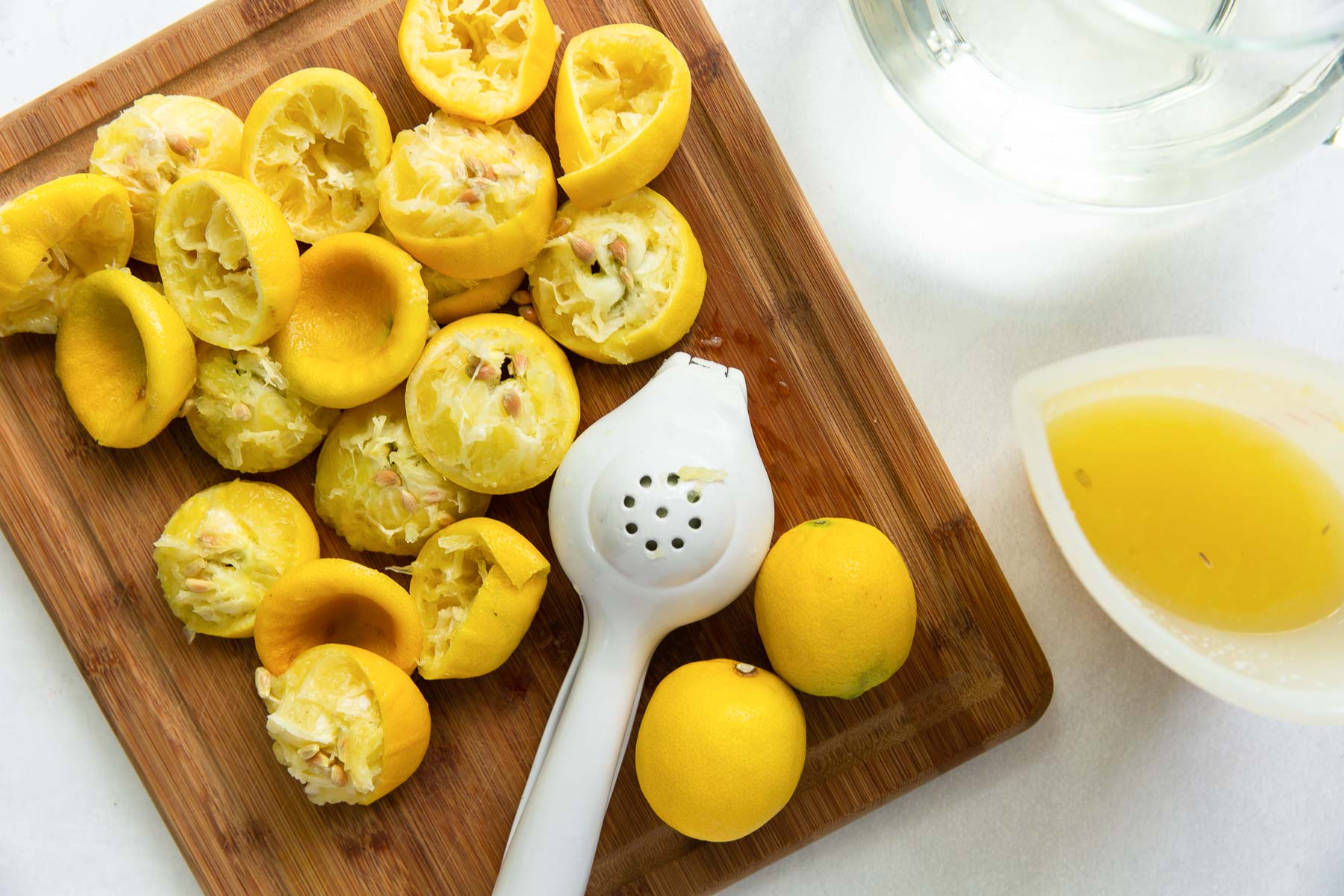 How to make lemonade. This Lemonade Recipe is made with fresh squeezed lemon juice for the best sweet-tart flavor. It's easy to make with just 3 ingredients. An ice-cold glass of this homemade lemonade is the perfect refreshing drink on a hot day! juiced lemons and juicer on a cutting board for lemonade